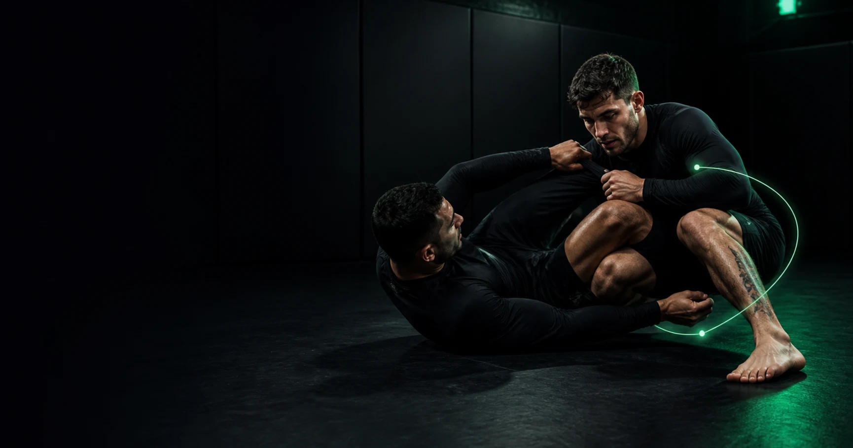 Grapplers work through a guard pass under restrained green mat lighting